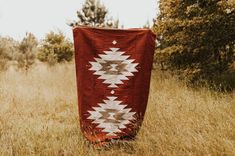 an old blanket is sitting in the middle of a field with tall grass and trees