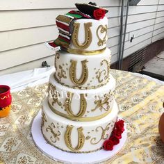 a three tiered wedding cake with red roses on the bottom and gold decorations around it