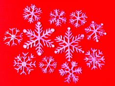 six snowflakes on a red background with white balls in the middle and one is pink