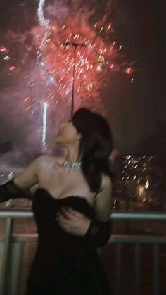 a woman in a black dress looking at fireworks