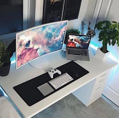 a desk with a laptop, monitor and keyboard on it next to a potted plant