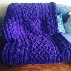 a purple blanket sitting on top of a blue couch