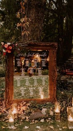 an outdoor ceremony with candles and a large mirror on the ground in front of it