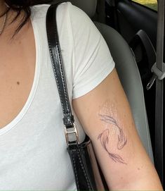 a woman with a tattoo on her arm in the back seat of a car,