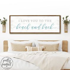 a bed with pillows and blankets in front of a wooden sign that says i love you to the beach and back