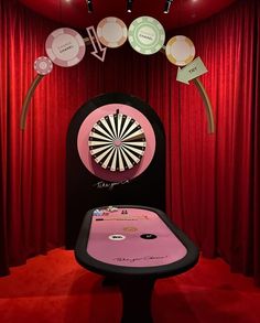 a table with a dart on it in front of a red curtain and some lights