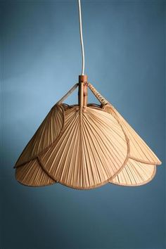 a bamboo lamp hanging from the ceiling in front of a blue wall with a white cord