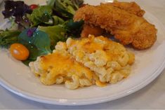 a white plate topped with macaroni and cheese next to salad