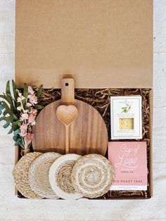 a wooden cutting board sitting on top of a table next to some bread and flowers