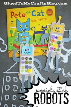 two popsicle stick robots are sitting next to a book with the title pete the cat on it