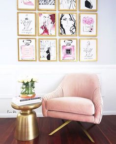 a pink chair sitting on top of a wooden floor next to a wall with pictures above it