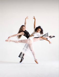 two women in white and black dance on their feet with one holding the other's leg