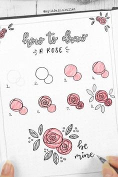 someone is drawing roses on a notebook with markers and pencils in front of them