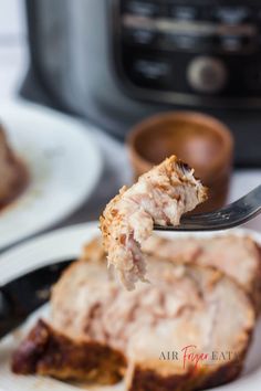 a piece of meat is being lifted from a plate with the rest of it in front of an instant pot roaster