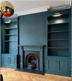 an empty living room with blue painted walls and fireplace in the center, surrounded by wood flooring