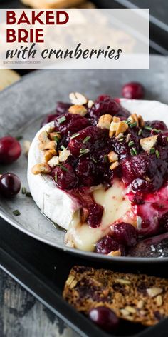 baked brie with cranberries and pecans on a plate next to crackers