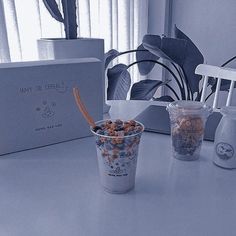 there are two cups on the table with cereal in them and one has a straw