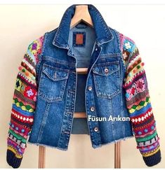 a blue jean jacket with multicolored crocheted sleeves and buttons on the back