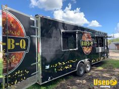 a black food truck parked in the grass