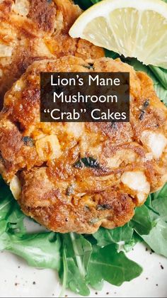 two crab cakes with lemon wedges and spinach leaves on the side that says lion's mane mushroom crab cakes