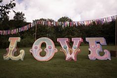 there are letters that spell out the word joy in front of some trees and bunting