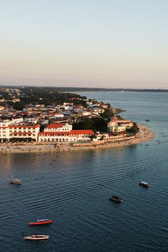 several boats floating on the water in front of an island with houses and buildings around it