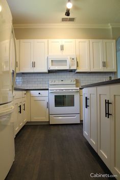 an empty kitchen with white cabinets and appliances