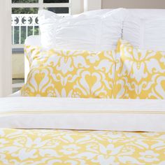 a bed with yellow and white pillows on top of it in front of a window