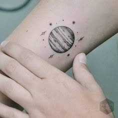 a woman's arm with a small tattoo on it that shows the planets and stars