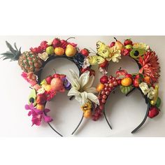 two mickey ears made out of fruit and flowers are shown on a white wall with butterflies