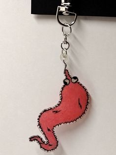 a red keychain hanging from the side of a white wall with a cartoon character on it