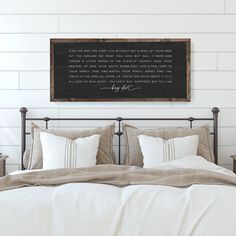 a bed with white sheets and pillows in front of a blackboard on the wall