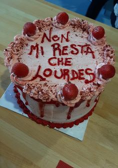 a cake with writing on it sitting on top of a wooden table next to a knife