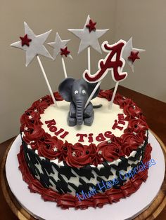 a red, white and black cake with an elephant on top is decorated with stars