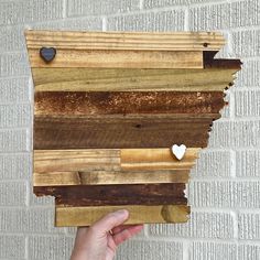 a person holding up a piece of wood with hearts on it