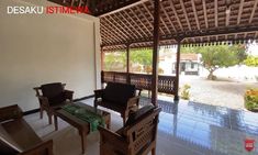 a living room filled with furniture under a wooden roof next to a stone floor covered patio