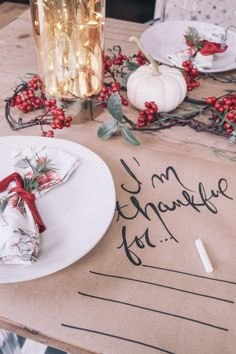 the table is set with plates, napkins and silverware for christmas dinner guests to enjoy