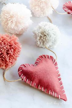 three pom - poms are on the table next to two heart shaped ornaments