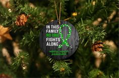 a wooden ornament hanging from a christmas tree with purple ribbon and pine cones