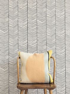 a chair with a pillow on top of it in front of a wallpapered background