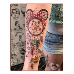 a person with a tattoo on their arm that has a mickey mouse head and dream catcher