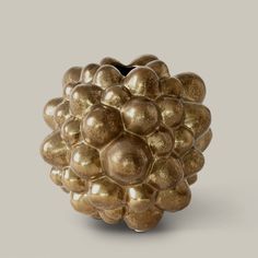 a gold vase with many balls in it's center on a gray background,