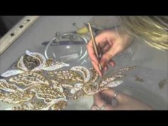 a woman is working on some gold jewelry