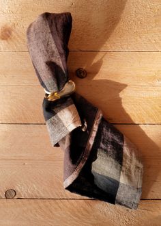 two towels folded up on top of a wooden floor next to a button and ring