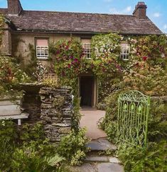 an old stone house with flowers growing all over it