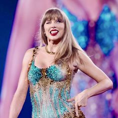 taylor swift performing on stage wearing a blue and gold corset with her mouth open