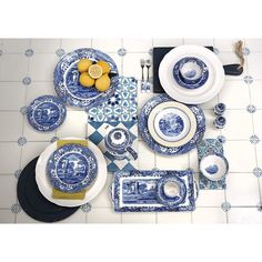 blue and white dinnerware is laid out on a table with lemons, plates, utensils and silverware