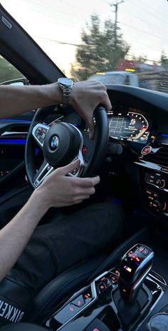 a man driving a bmw car on the road with his hands on the steering wheel