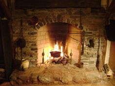 an old stone fireplace with pots and pans on the fire place next to it