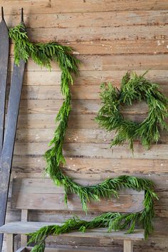 a wooden bench sitting next to a wall covered in green plants and greenery hanging from it's sides